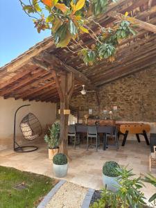 a patio with a table and chairs under a wooden ceiling at Le 1881 Ampuis in Ampuis