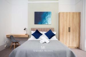 a bedroom with a bed with blue pillows and a desk at Luxury 6BR Ensuite - Contractors & Groups Stay - Parking in Sunderland