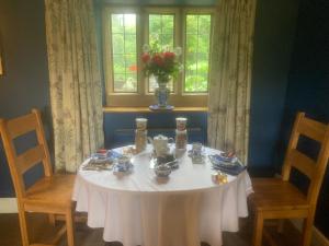 a table with a white table cloth and a vase of flowers at Rock House BNB in Bakewell