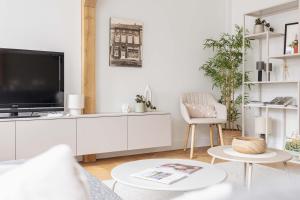 a white living room with a tv and a couch at Vakantiewoning Gast in Borgloon