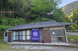 a small building with a purple banner on it at 花子のいえ hanako's house in Amidaji