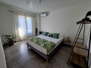 a bedroom with a bed with green pillows and a ladder at Ti case Margot - Maison avec piscine à Manapany in Saint-Joseph +8 photos