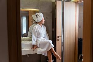 a woman sitting on a bathroom sink in front of a mirror at Mary Hotel & Mary Royal Suites in Platanes +47 photos