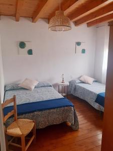 a bedroom with two beds and a chair and a chandelier at Casa Valeriana Guijosa in Guijosa