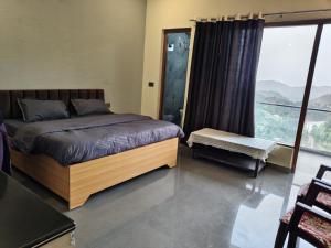 a bedroom with a bed and a large window at Singh Kainchi Dham Villa in Bhowāli