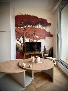 a living room with a table and a tree mural at Elegance Bretonne in Pléneuf-Val-André