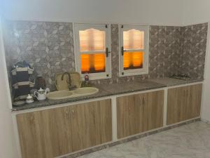 a bathroom with a sink and two windows at Appartement Al Hanine in Douz