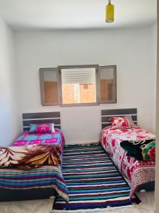two beds sitting next to each other in a room at Appartement Al Hanine in Douz +3 photos