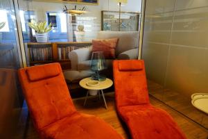 two orange chairs and a table in a room at Ostseelandhaus DHH Wendy 1 in Proseken +12 photos