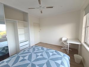 a bedroom with a bed and a desk and a window at Spacious and Comfortable Queen Room - NM1 in Merrylands