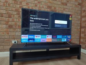 a television on a stand in front of a brick wall at Spacious and Comfortable Queen Room - NM1 in Merrylands