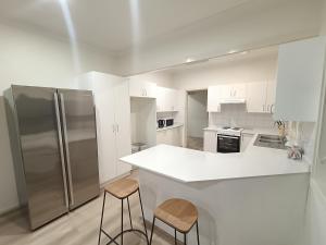 a kitchen with a stainless steel refrigerator and two stools at Spacious and Comfortable Queen Room - NM1 in Merrylands