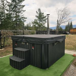 a black outhouse with a table on the grass at Belvedere Panaci in Coverca