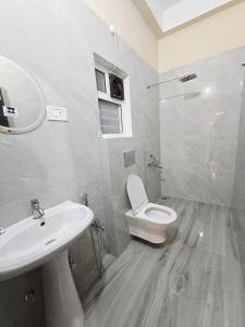 a bathroom with a white toilet and a sink at Mong Mao Manor in Guwahati +11 photos