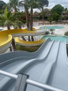 a slide at a water park with palm trees at Mobilhome Ligaropa climatisé 3 ch 6 pers camping des 7 fonts in Agde