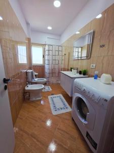 a bathroom with a washing machine and a toilet at Asea Apartaments in Golem +28 photos