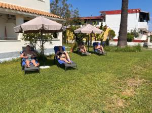 a group of people sitting in lawn chairs under umbrellas at Dolphin Apt & Studios -Near the Beach in Roda +100 photos