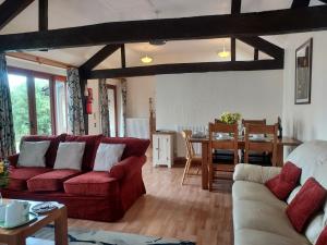a living room with a red couch and a table at Farm Stay with animal experiences, 30 minutes to Exmoor & Beaches, Pet friendly, Outdoor heated pool, Games barn, fast WiFi and parking in Barnstaple