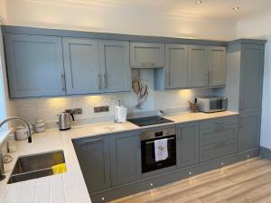 a kitchen with blue cabinets and a sink at Exmouth Devon Luxurious Flat OverlookingThe Sea in Exmouth +24 photos