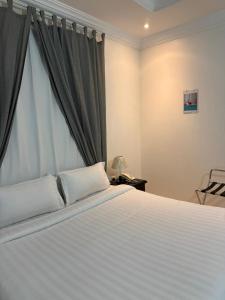 a bedroom with a white bed and a window at رمادان تربة للشقق المخدومة in Turbah