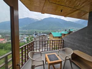 a balcony with a table and chairs and mountains at The Park Green Resorts in Manāli