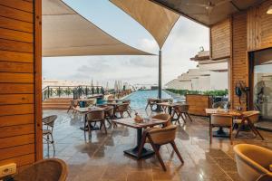 a restaurant with tables and chairs and a view of the water at Azur White Resort Ras El Hekma in Zāwiyat al ‘Awwāmah
