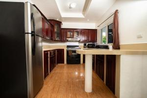 a kitchen with wooden cabinets and a black refrigerator at Casa Herminia in Omoa