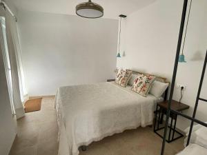 a white bedroom with a bed and a lamp at Entre Murallas in Doña Mencía