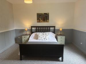 a bedroom with a black bed with two night stands at Pion La Grange - cottage barn conversion in Castelnau-dʼAuzan
