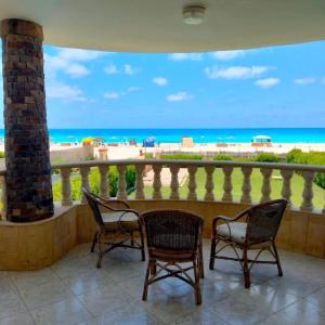 a balcony with two chairs and a view of the beach at فيلا غرناطه الساحل الشمالي in Dawwār al Ḩajj Aḩmad