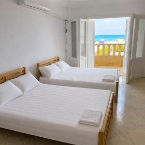 two beds in a bedroom with a view of the ocean at فيلا غرناطه الساحل الشمالي in Dawwār al Ḩajj Aḩmad +13 photos