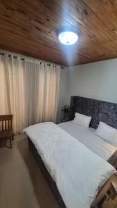 a bedroom with a large bed with a wooden ceiling at Kaze Consolidate Home Inn in Kigali