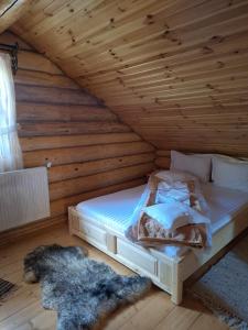 a bedroom with a bed in a wooden room at Cabana La Bălănuț din Bucovina in Colacu
