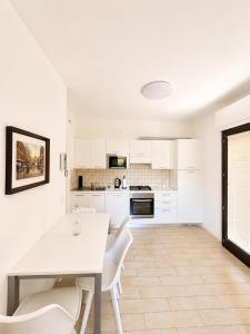 a white kitchen with a white table and chairs at Lotus in Lenno