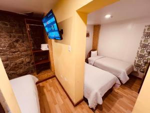 a small room with two beds and a flat screen tv at PAKARI Wasi in Cusco