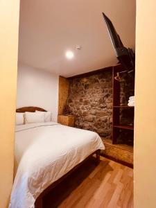 a bedroom with a bed and a stone wall at PAKARI Wasi in Cusco +24 photos
