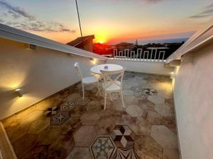 a balcony with a table and chairs and the sunset at Godano Rooms in Drapia