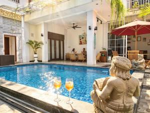 a villa with a swimming pool with glasses of wine at Brady's B&B Close To Sanur Beach in Sanur