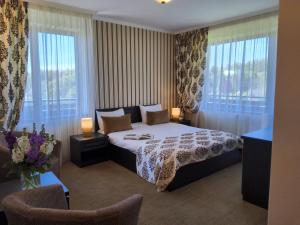 a hotel room with a bed and two windows at Pensiunea Toscana in Braşov