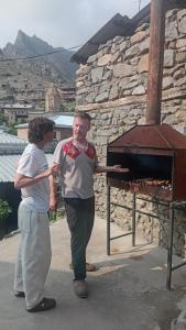 a woman standing next to a man in front of an oven at Ani guest house in Meghri