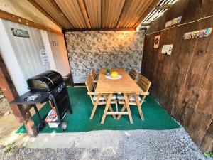 a grill and a wooden table and chairs in a house at Casa del Sole Apartments - Ruhig - Nähe Interlaken in Spiez