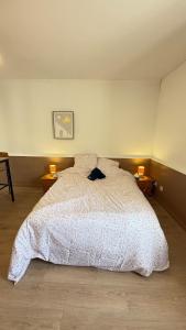 a bedroom with a large white bed with two lamps at joli petit studio breval in Bréval