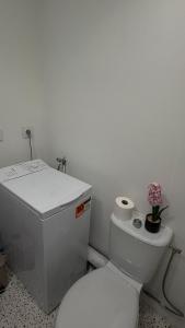 a white bathroom with a toilet and a toilet paper dispenser at joli petit studio breval in Bréval