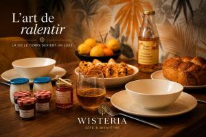 a table topped with dishes of food and a bottle of wine at Wistéria #Piscine #Terrasse privée #Route des vins in Azé