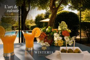 a table with two glasses of orange juice and a flower arrangement at Wistéria #Piscine #Terrasse privée #Route des vins in Azé