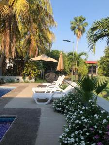a group of lounge chairs and an umbrella and some flowers at Quinta Temiki in San Pedro Masahuat