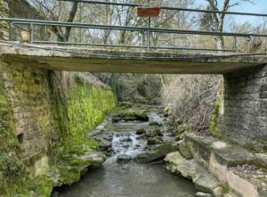 a bridge over a stream with a creek at La Grotta in Hinkel +2 photos