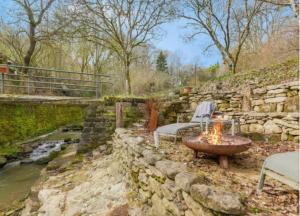 a stone wall with a table and chairs next to a river at La Grotta in Hinkel