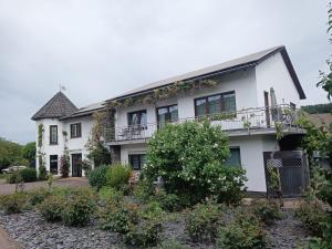 a white house with a balcony at Weingut Villa Raevenhof in Ayl