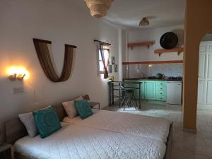 a bedroom with a white bed and a kitchen at Sunshine in Maltezana